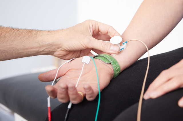 Kabel an einer Hand, der Neurologe Dr. Draeger testet die Leitfähigkeit der Nerven (Elektronneurografie)
